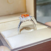 Side view of raised orange center stone and clear accents on ring