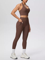 Model poses in brown halter activewear set with hand at waistband