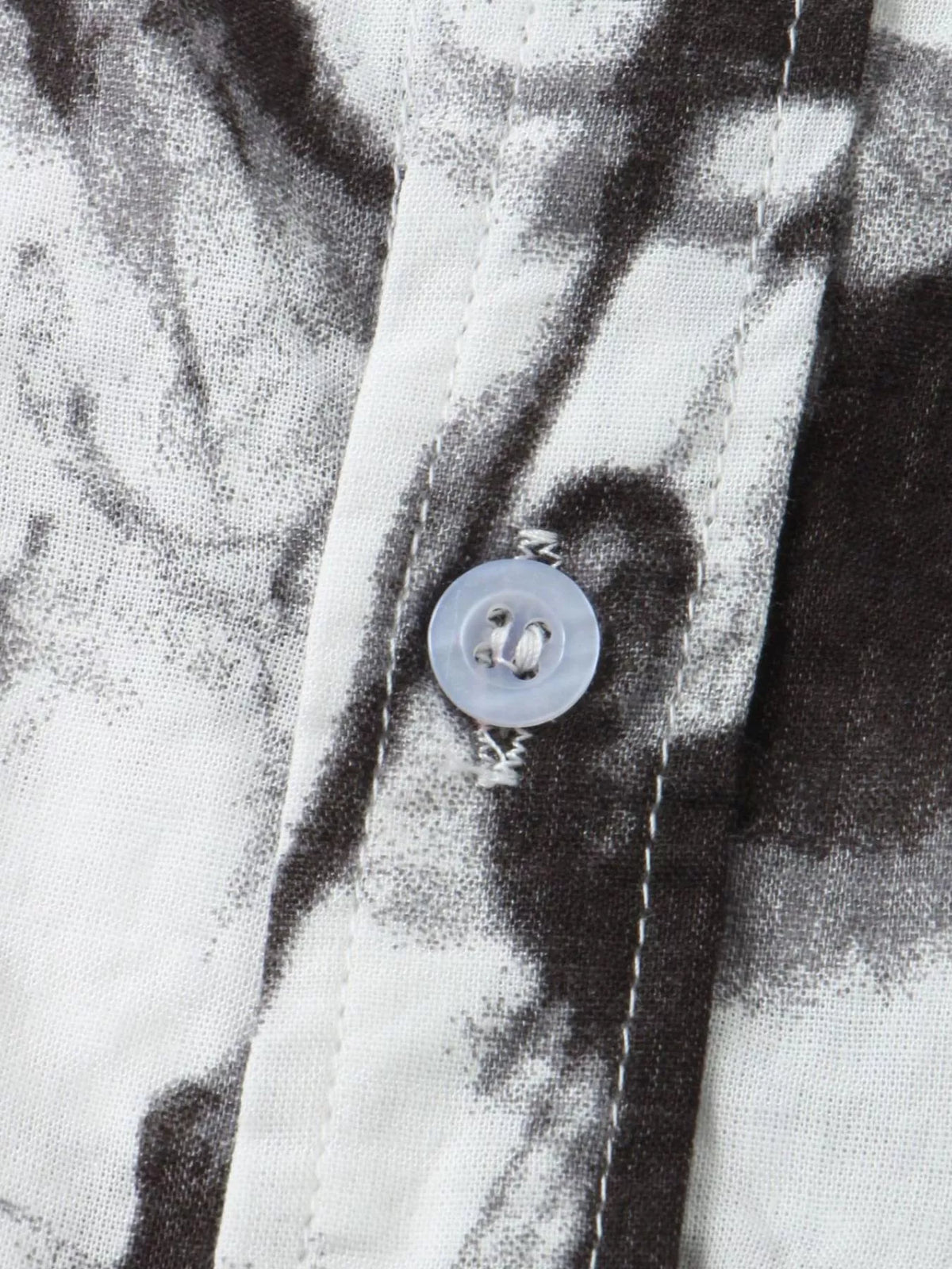 Close-up of black abstract print and button on white shirt fabric