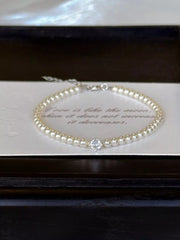 Pearl bracelet laid inside a dark jewelry box with a card beneath it.