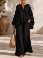 Woman wearing a black notched-neck top with matching wide-leg pants, full-length view.