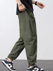Angled side view of olive joggers with a rear patch pocket and elastic cuffs.