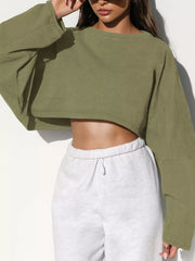 Front view of an olive green cropped sweatshirt with long sleeves, worn with light gray sweatpants.