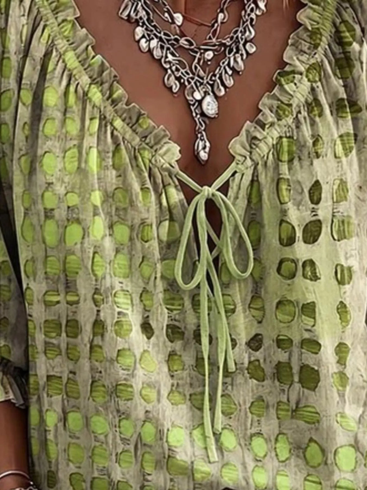 Close-up of the green blouse's ruffled neckline and tie fastening.