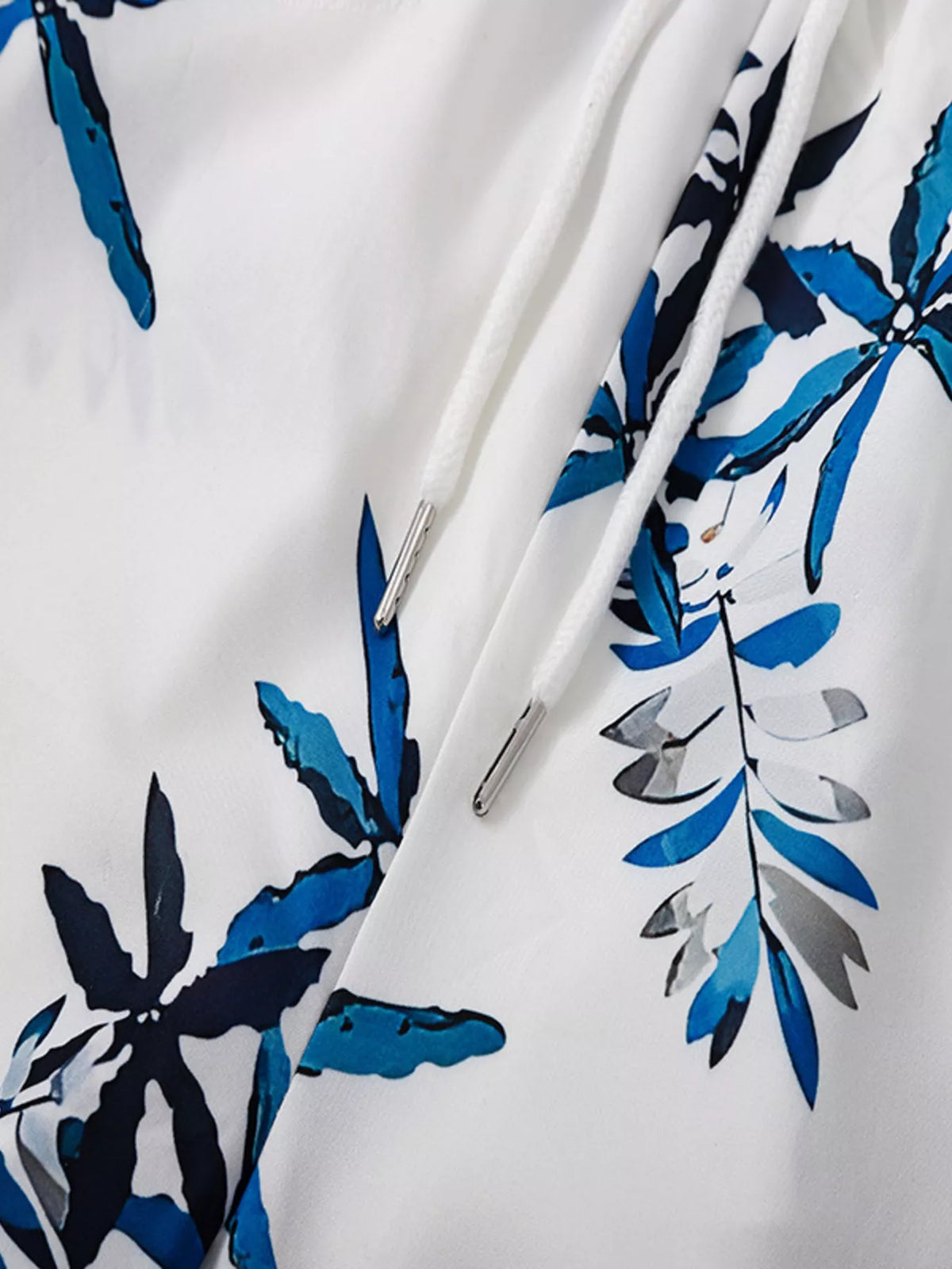 Close-up of blue tropical leaf motifs on white fabric