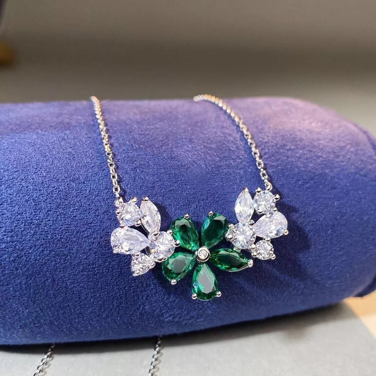 Green flower pendant necklace displayed on blue cushion