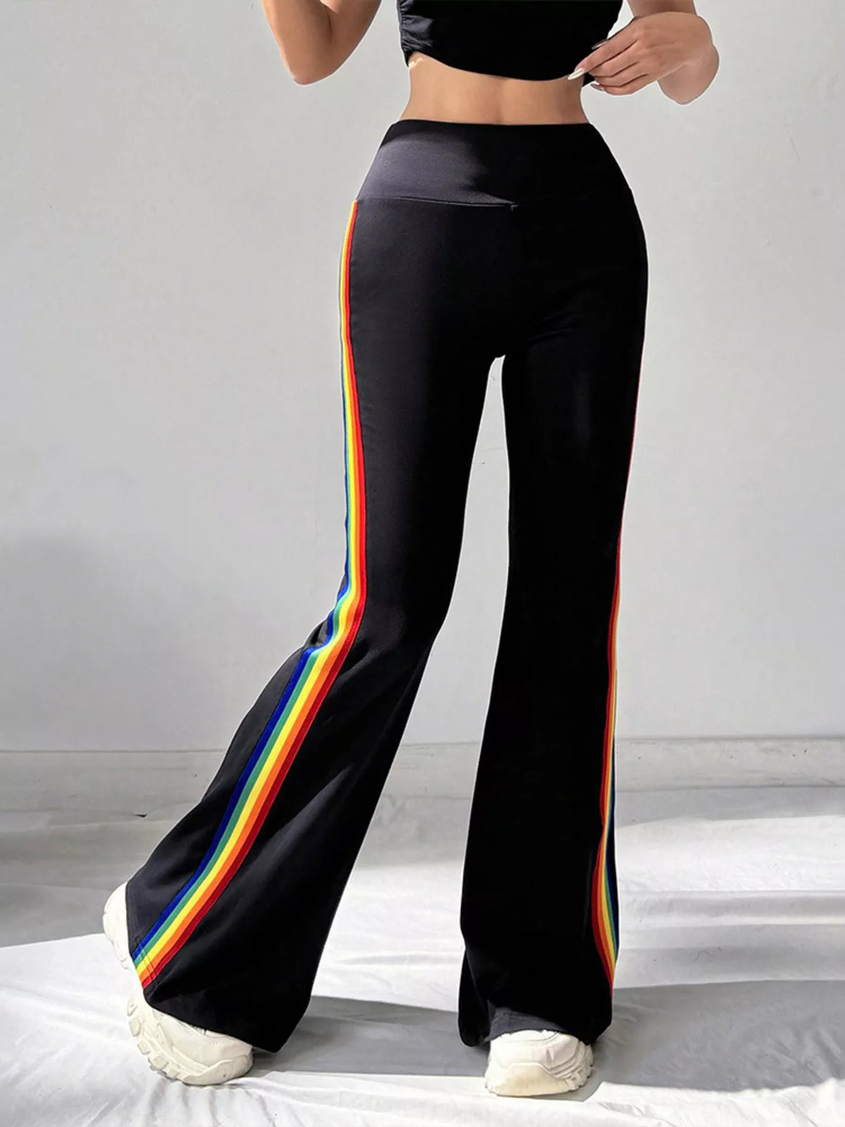 Black flare pants with rainbow stripes, angled view