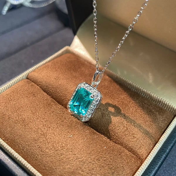 Angled view of turquoise-blue rectangular pendant necklace resting in brown-lined box