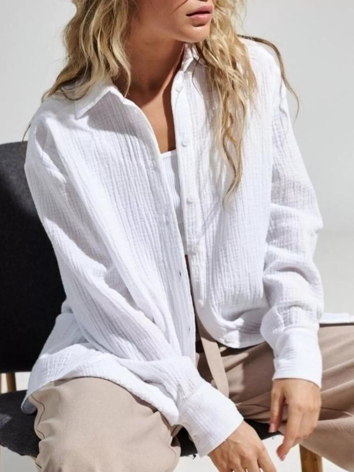 Seated model in loose white gauze shirt and light trousers.