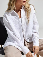 Seated model in loose white gauze shirt and light trousers.