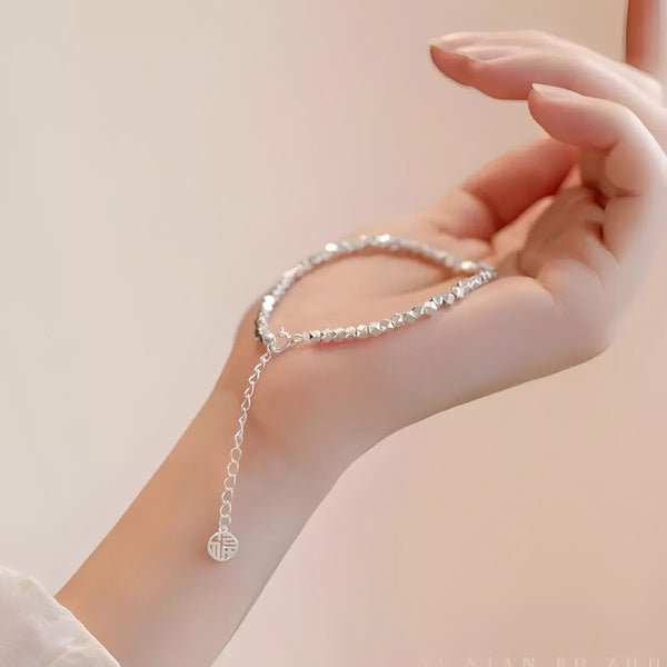 Geometric silver chain bracelet with adjustable extension worn on wrist