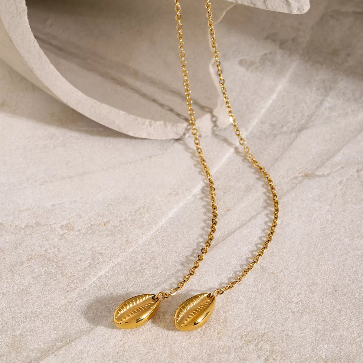 Gold Y necklace arranged in two long loops on light fabric