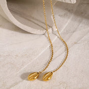 Gold Y necklace arranged in two long loops on light fabric