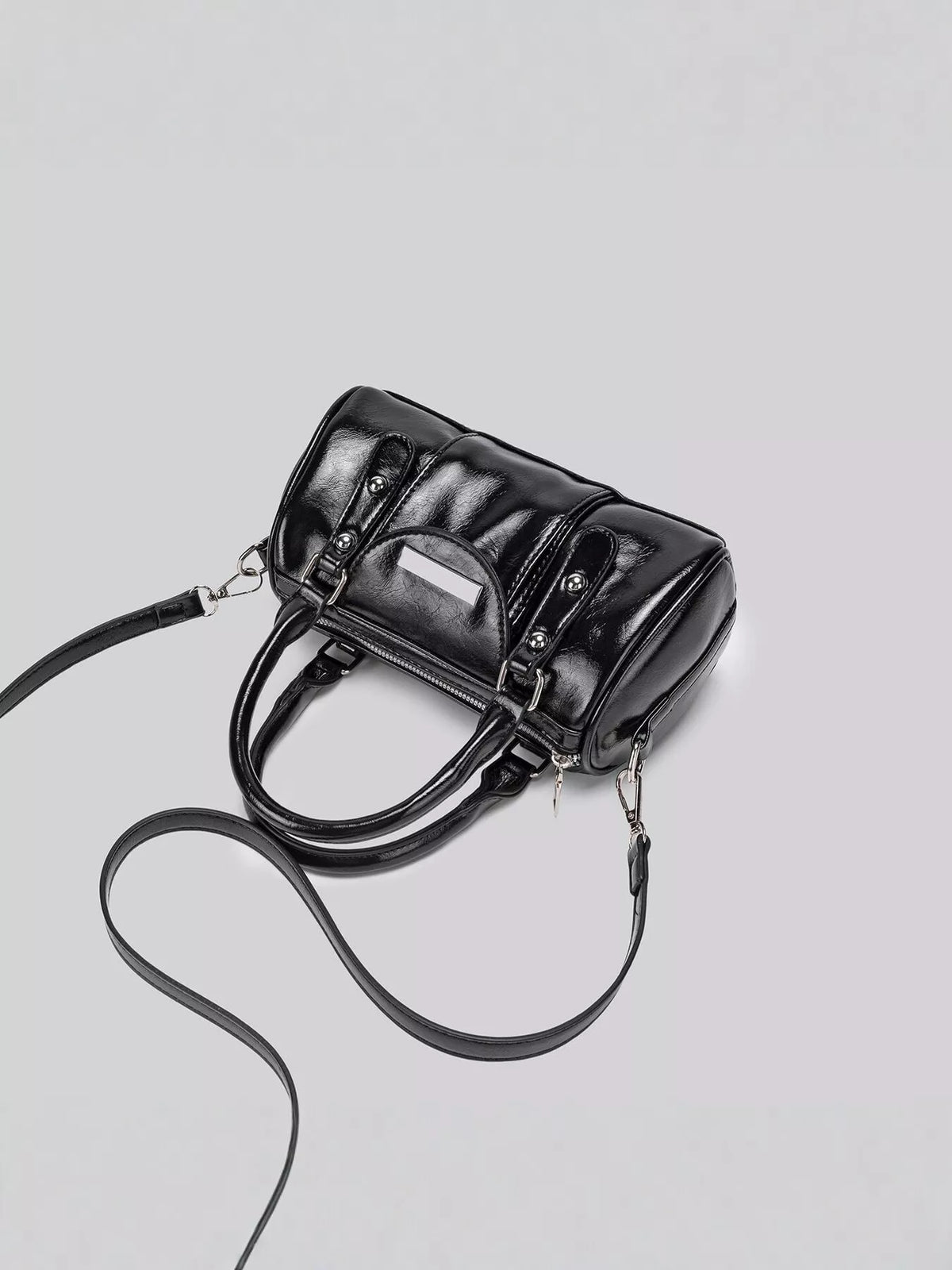 Top-down angled view of the black Boston bag with the long crossbody strap laid beside it.