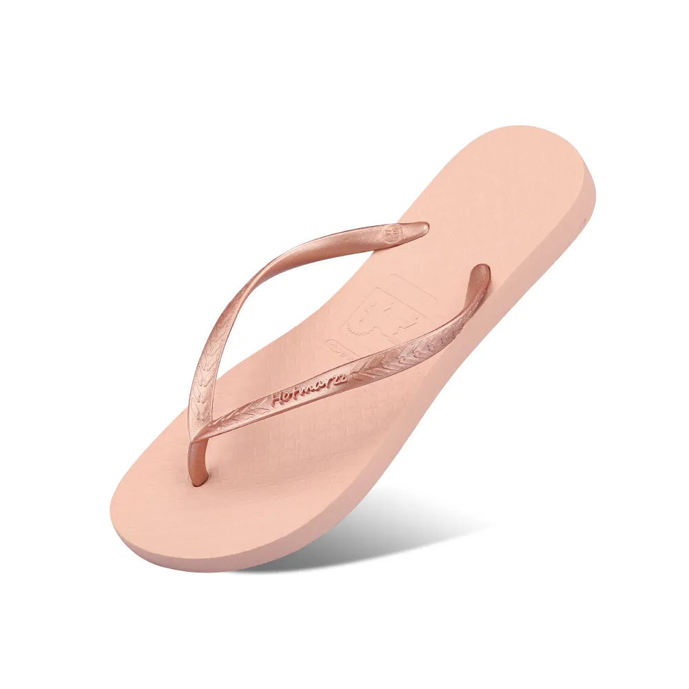 Peach flat flip-flop with rose-coloured toe-post straps, angled view