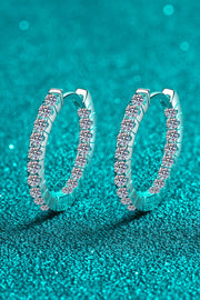 Moissanite 925 Sterling Silver Huggie Earrings — Angled view of moissanite huggie hoops on teal background