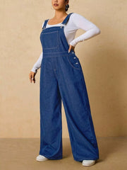 Angled view of medium blue denim overalls with one hand resting at the waist.