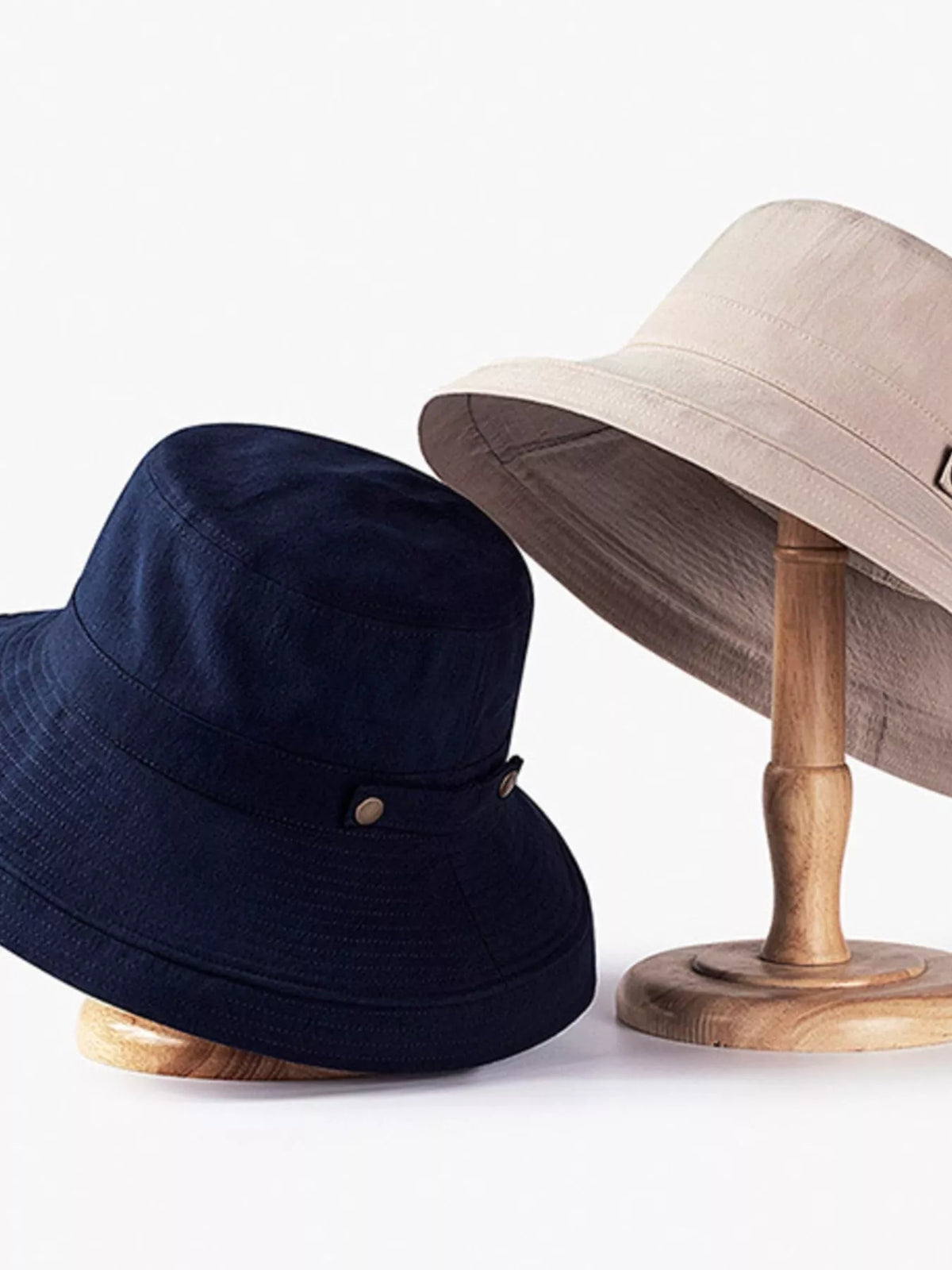 Navy and beige wide-brim sun hats shown on display stands.
