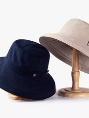Navy and beige wide-brim sun hats shown on display stands.