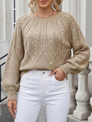 Front view of beige cable-knit sweater with one hand in pocket