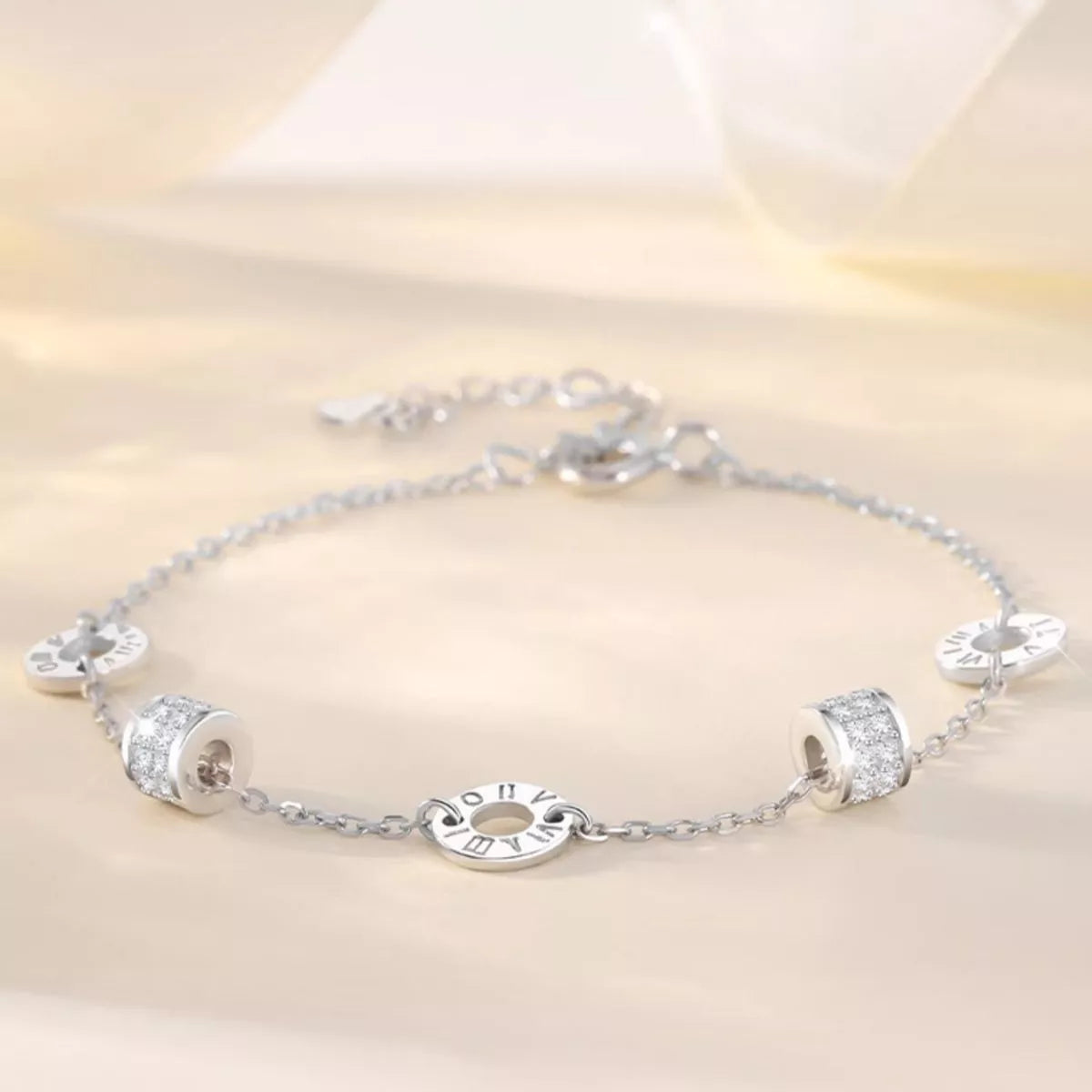 Silver geometric chain bracelet with circular and rectangular accents displayed flat