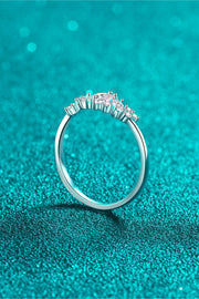 Rhodium-tone ring viewed from the back, showing its raised center setting against teal fabric