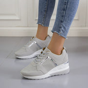 Pair of gray wedge sneakers worn with jeans