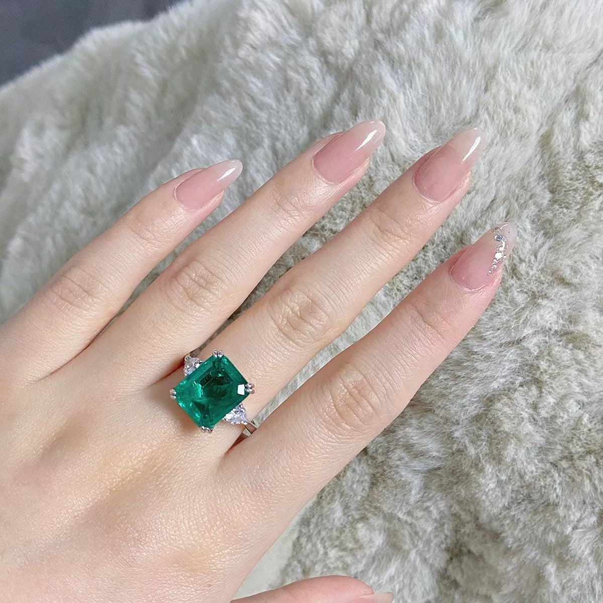Green rectangular zircon ring displayed on a hand.