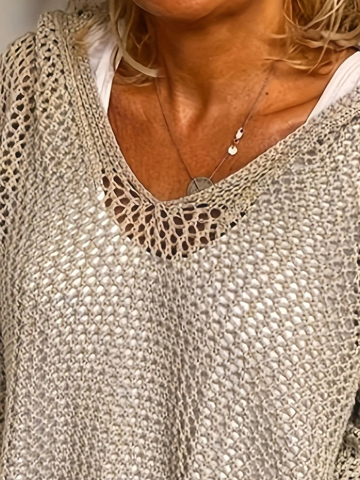 Close front view of a taupe knit cover-up showing its V-neck and open weave.