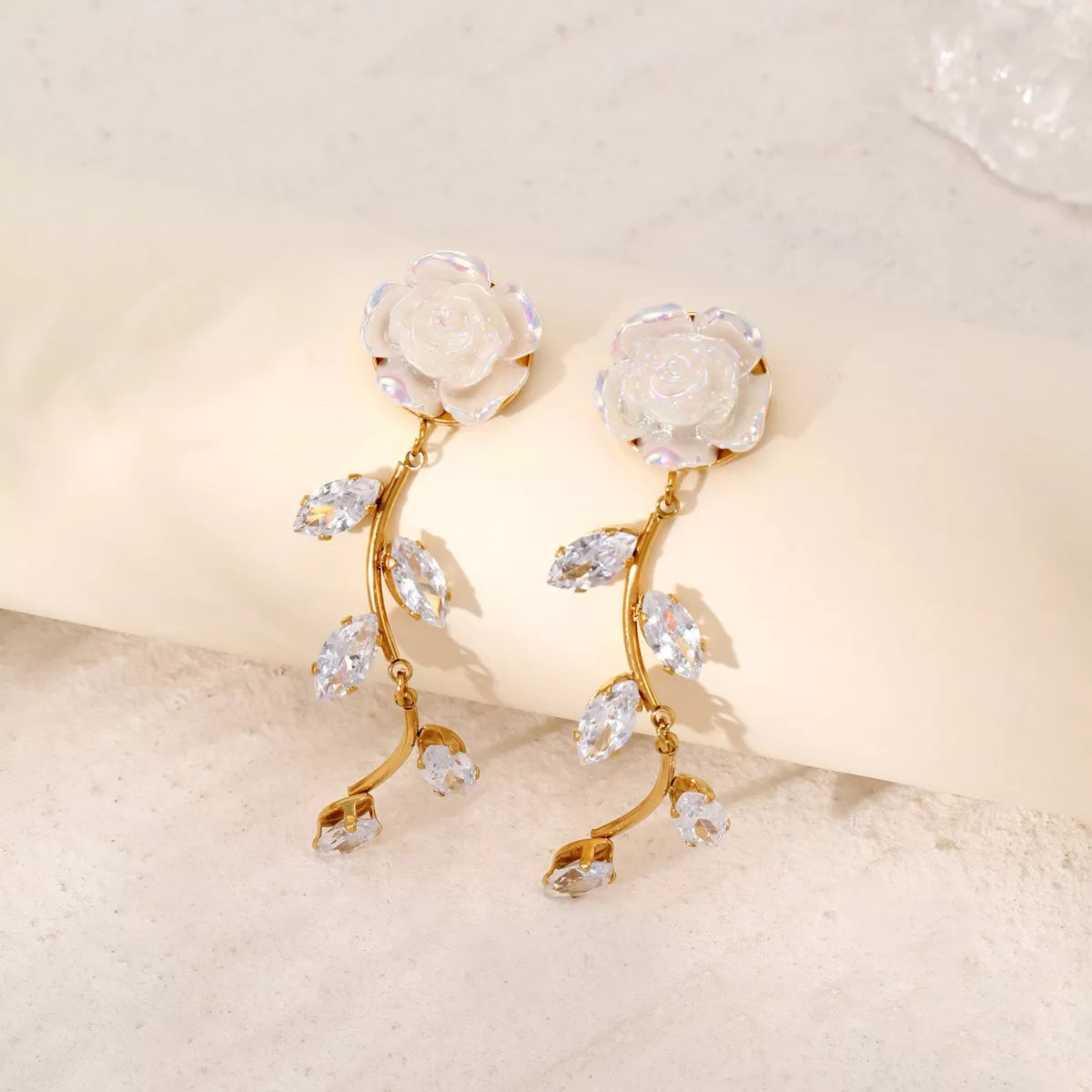 Pair of gold-tone flower drop earrings shown upright against a pale backdrop