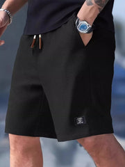Black waffle-textured shorts shown on a model with a hand in the side pocket