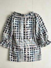 Back of the beige and blue printed blouse laid flat, showing gathered neckline.