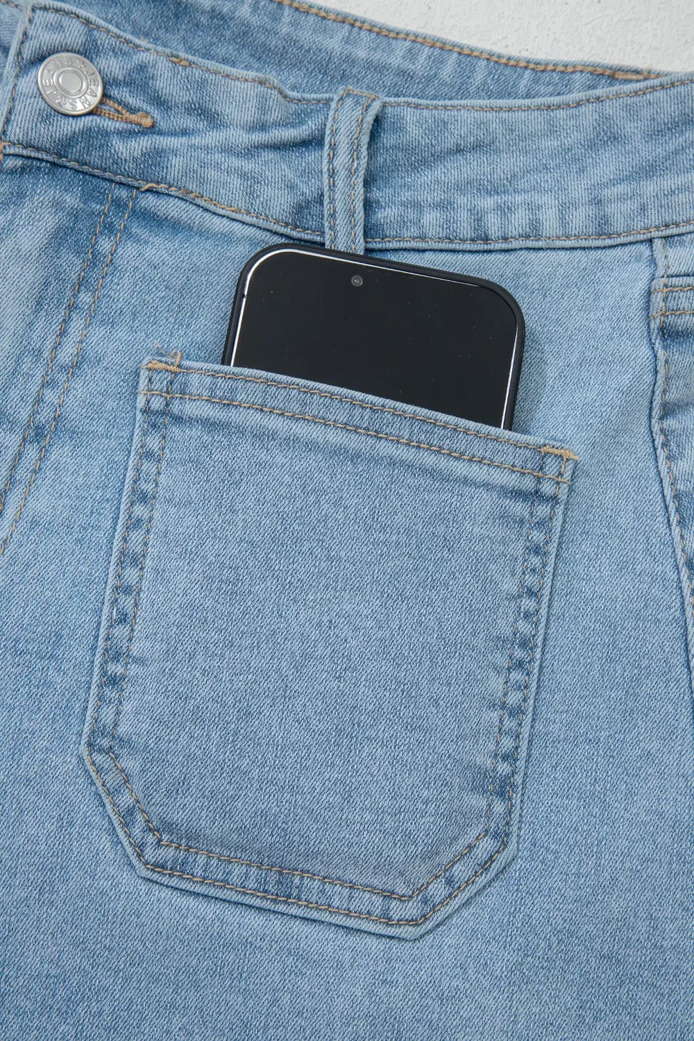 Close-up of phone in back patch pocket of denim shorts