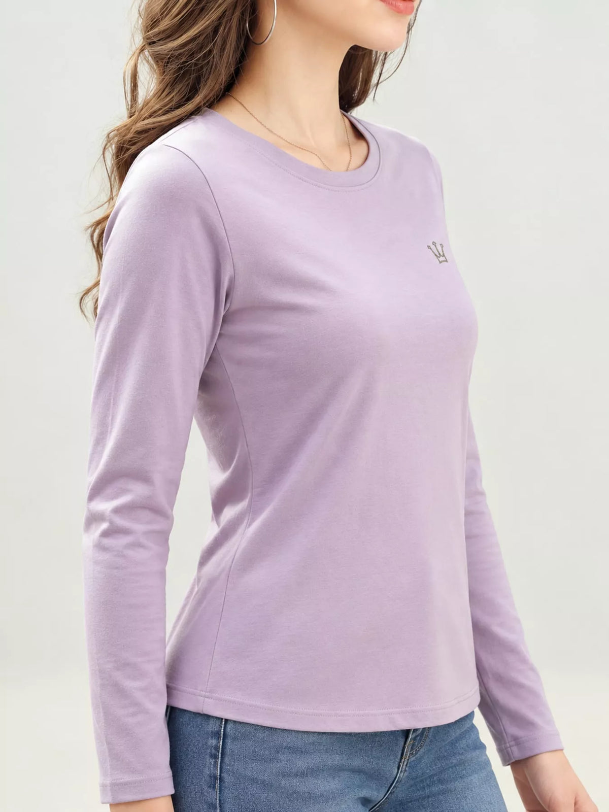 Lavender long-sleeve T-shirt with small crown emblem, shown on a model from the front at an angle.