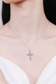 Silver-tone cross pendant necklace worn above a white neckline