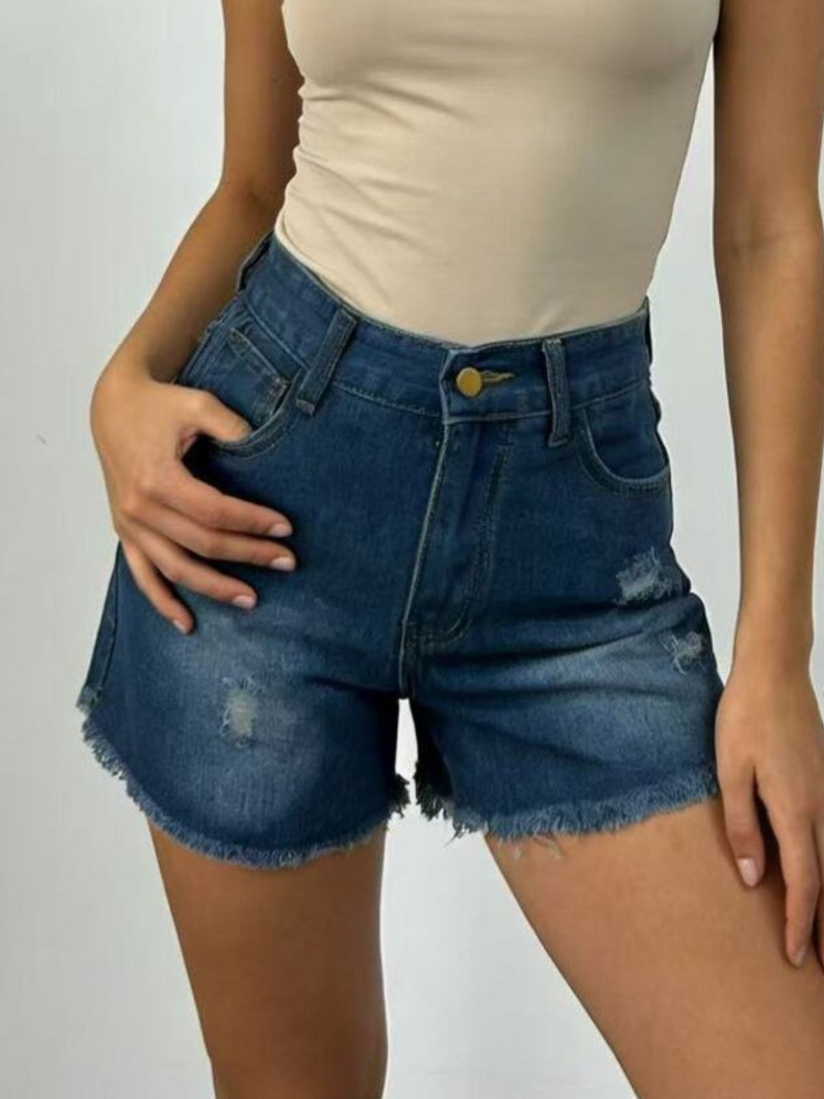 Model wearing dark-wash denim shorts with frayed hems