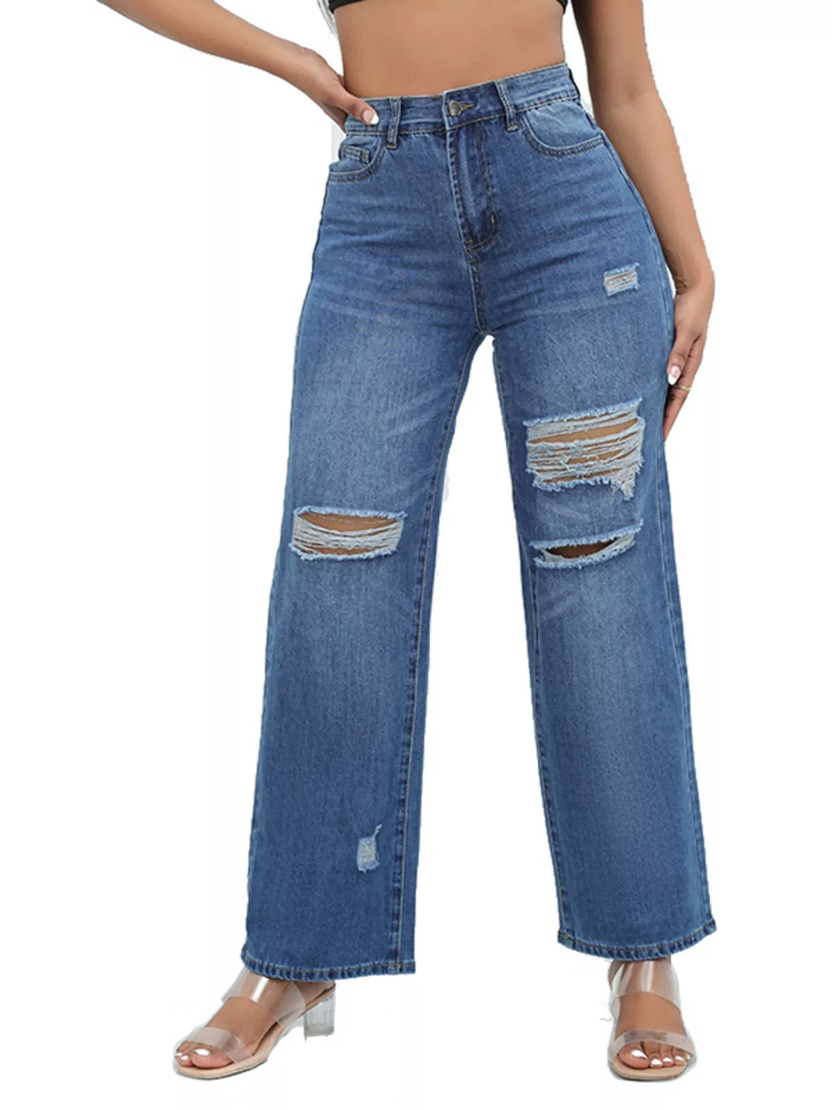 Dark blue ripped jeans isolated on white showing wide legs and clear-strap heels