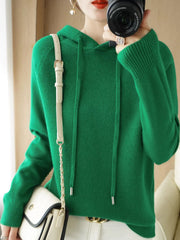Emerald green hooded sweater shown in a front mirror photo with a cream shoulder bag.