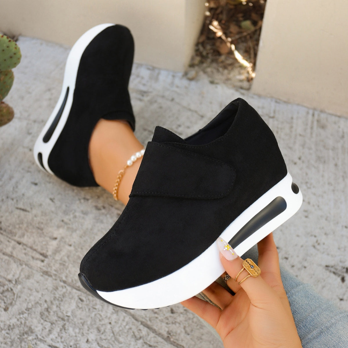 Black platform slip-on sneaker held to show the dark outsole