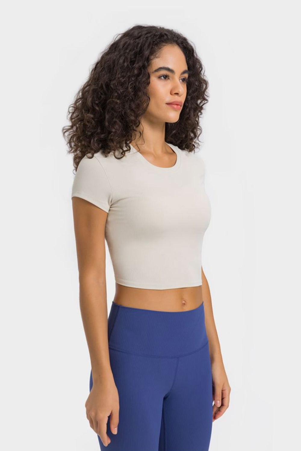 Model in ivory cropped T-shirt and blue leggings, three-quarter view
