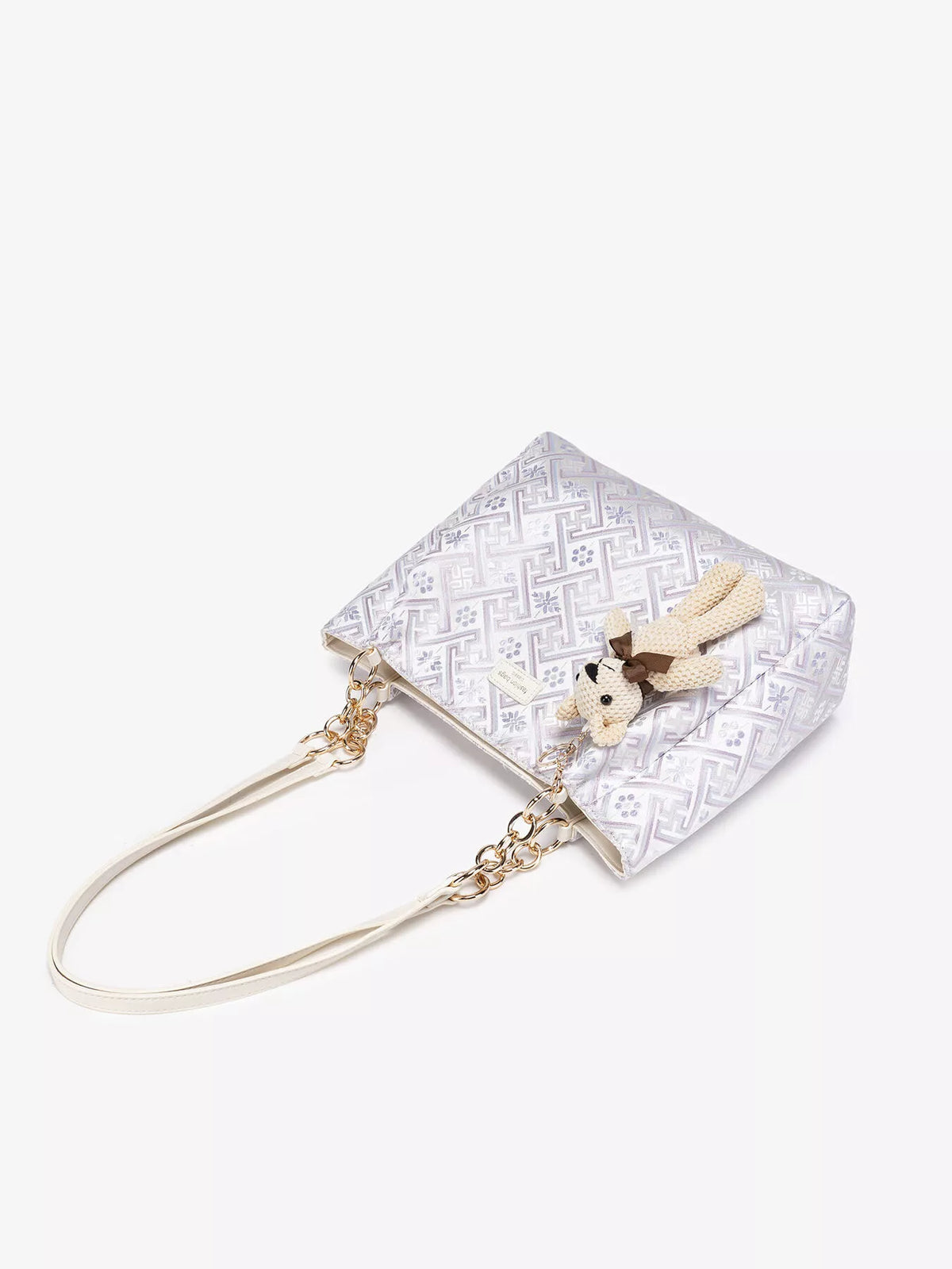 Top view of pale jacquard tote with teddy bear charm