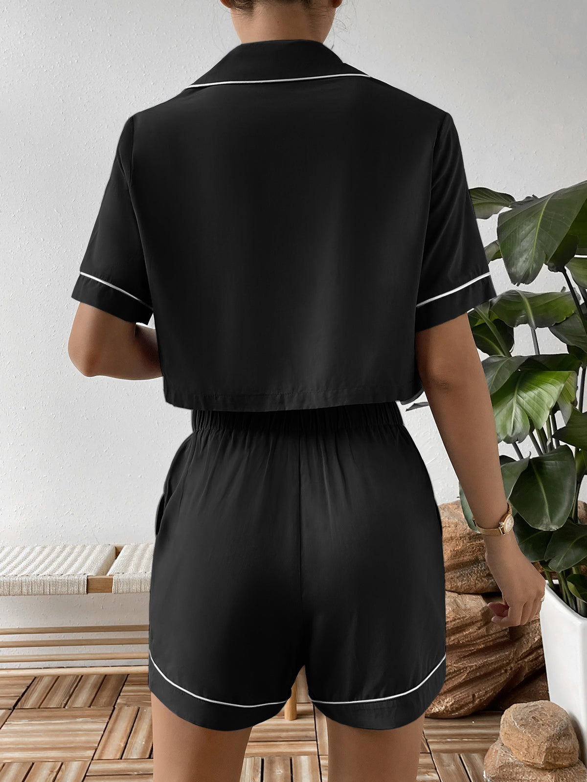 Back view of black cropped shirt and shorts with white piping