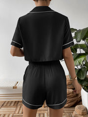 Back view of black cropped shirt and shorts with white piping