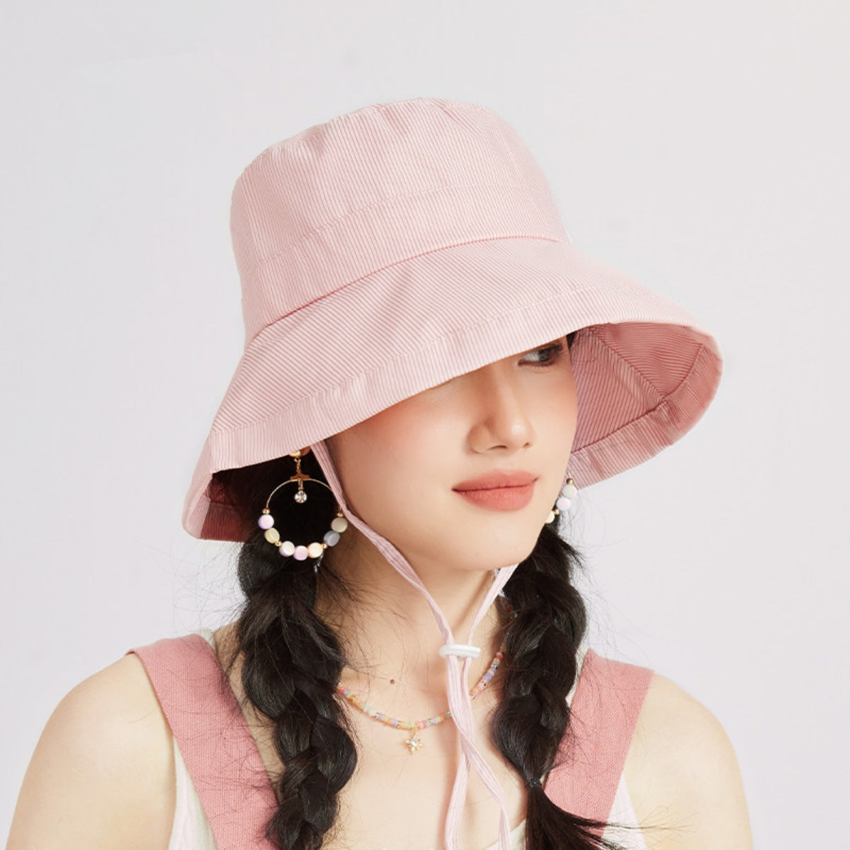 Model wearing a pink wide-brim sun hat with a chin tie.