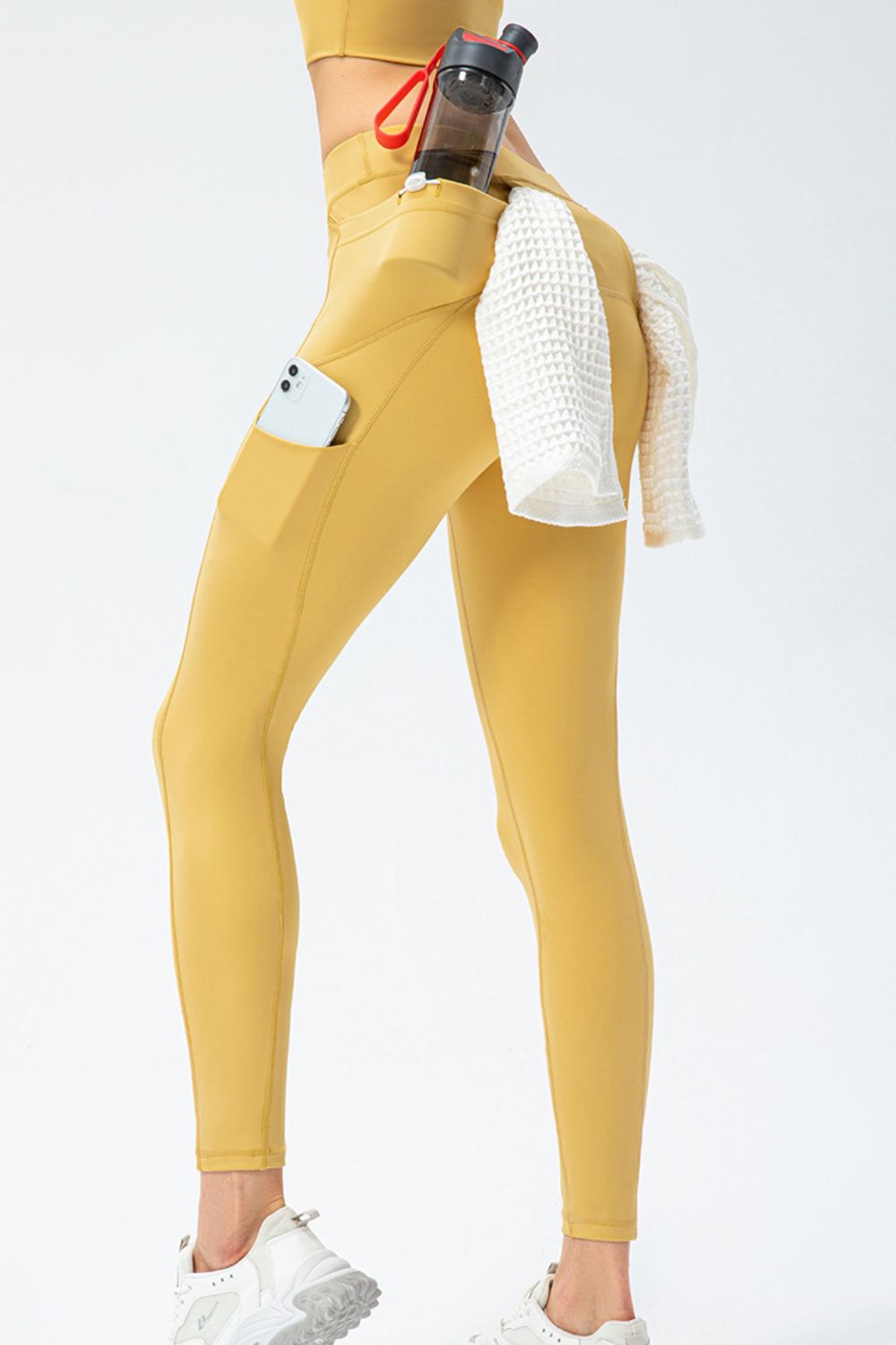 Mustard yellow high-waist leggings with rear and side pockets, phone and towel in side pockets