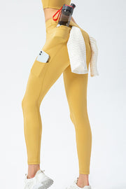 Mustard yellow high-waist leggings with rear and side pockets, phone and towel in side pockets