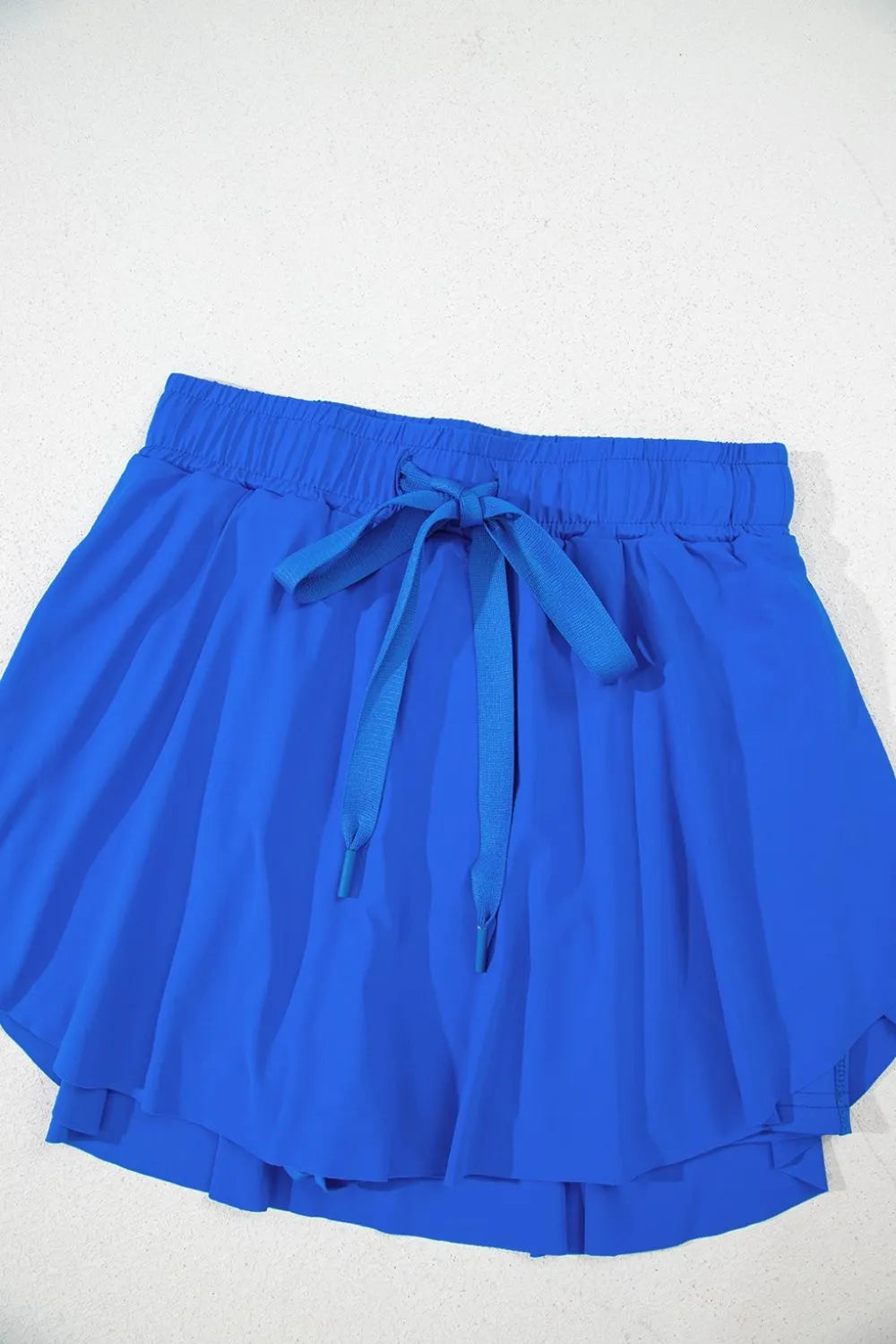 Blue skort laid flat to show gathered waistband and flared skirt
