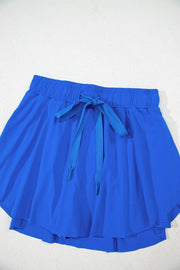 Blue skort laid flat to show gathered waistband and flared skirt