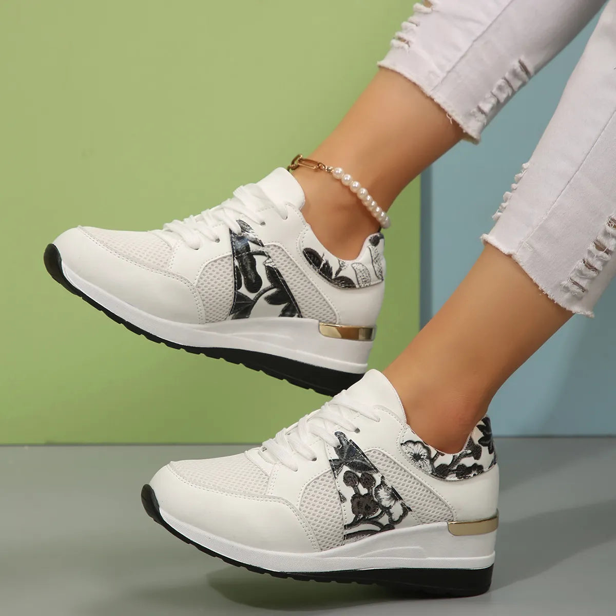 White sneakers with black floral panels shown from the side on feet
