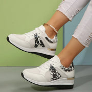 White sneakers with black floral panels shown from the side on feet